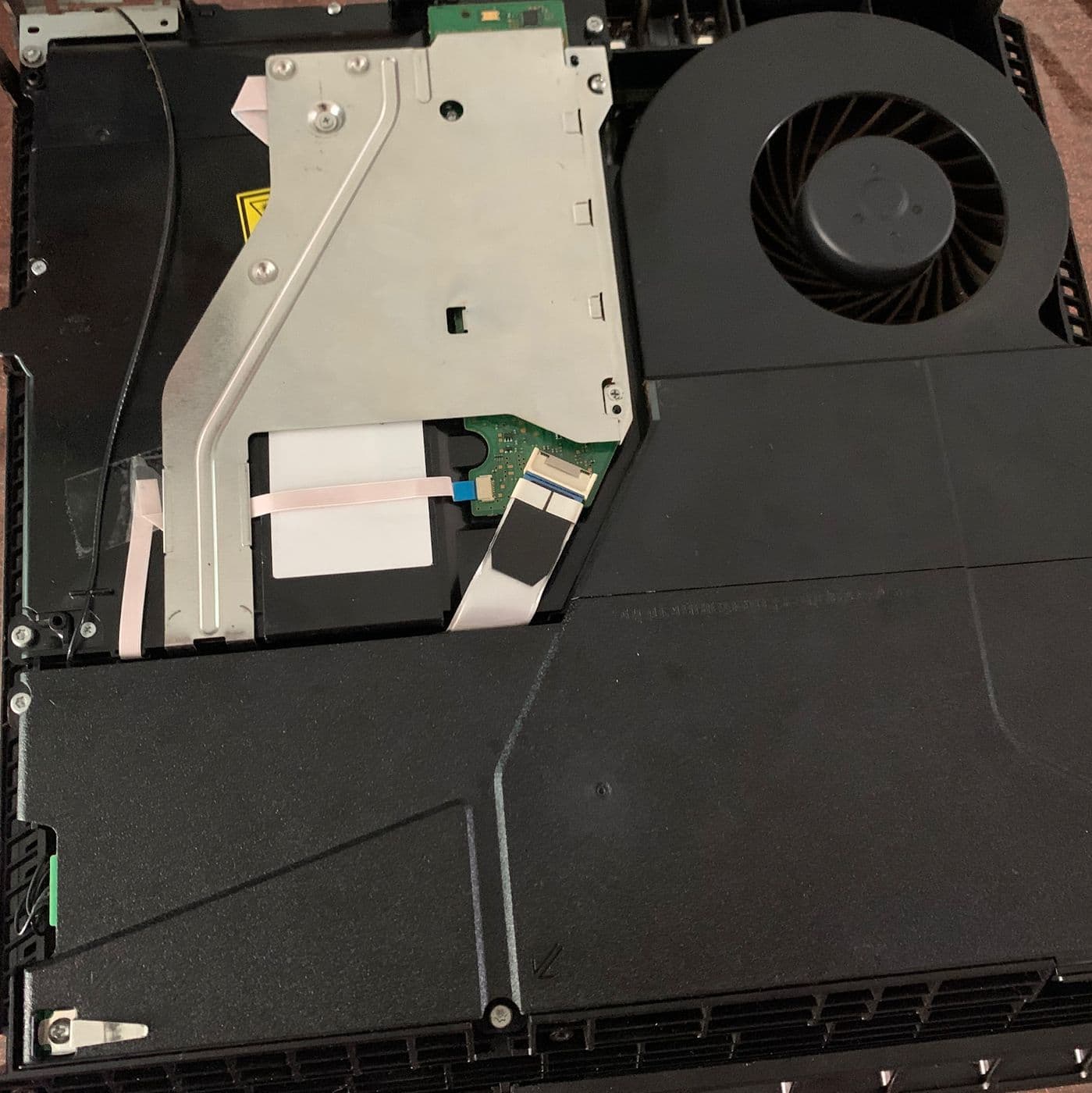 A games console opened up, showing the disc drive and cooling fan